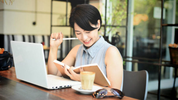 short hair woman smiling while looking at her notebook