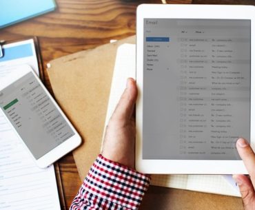 man holding digital table while reading email