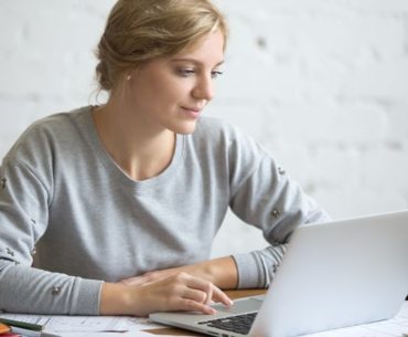 woman smiling while working on his laptop