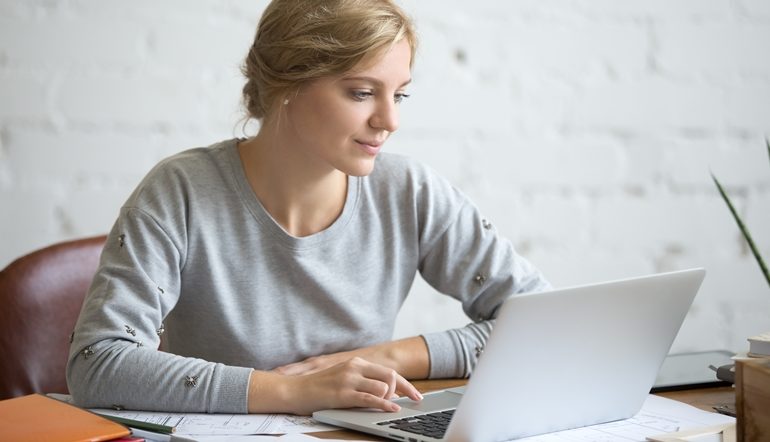 woman smiling while working on his laptop