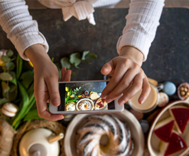 woman holding phone taking photos of her food