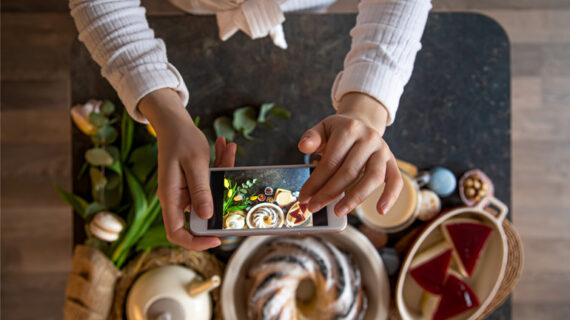 woman holding phone taking photos of her food