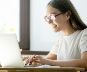 young female smiling in front of her laptop
