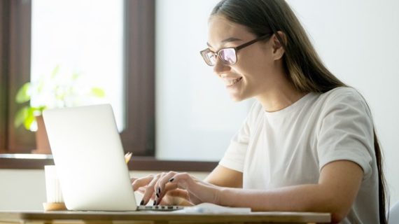 young female smiling in front of her laptop