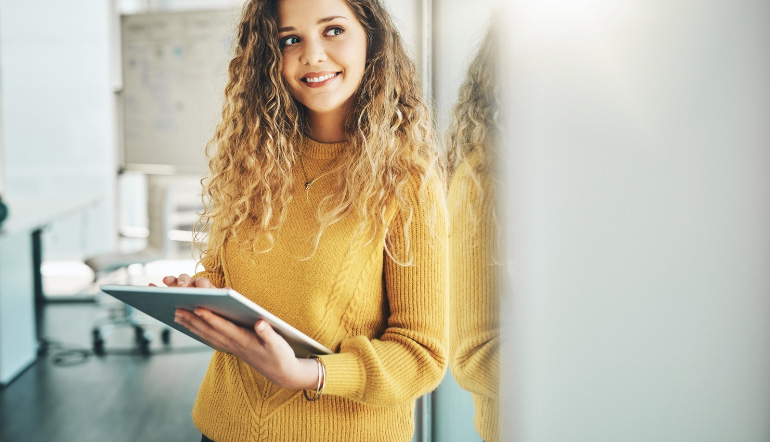 cheerful woman thinking while holding tablet