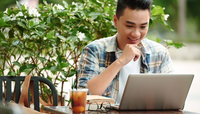 thrilled asian man checking his laptop