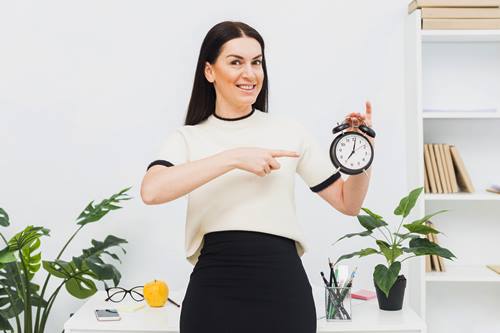 woman smiling while holding alarm clock