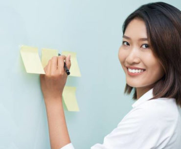asian woman writing on sticky notes