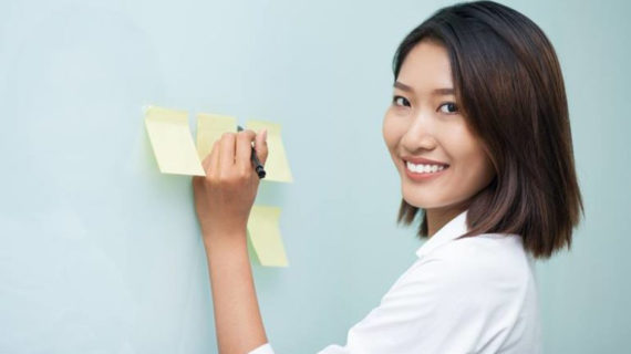 asian woman writing on sticky notes