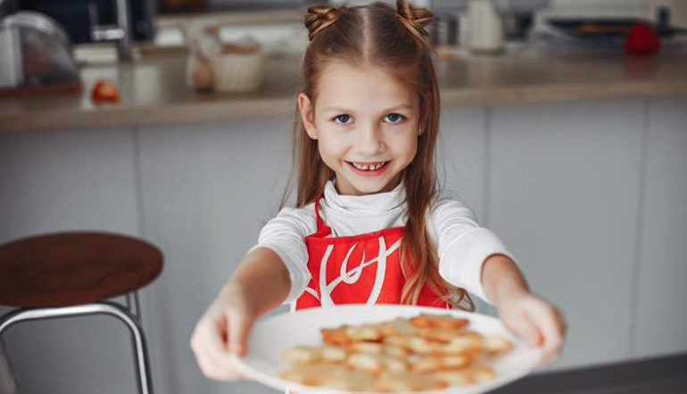 adorable little girl holding plate of cookies