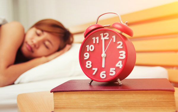 red alarm clock on top of a red book