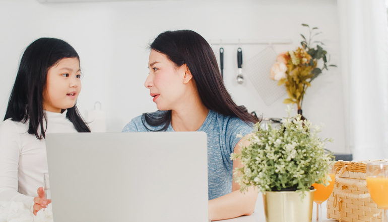 mom woking on her laptop while talking to her daughter