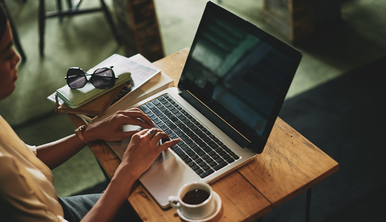 woman sitting in cafe and working on laptop