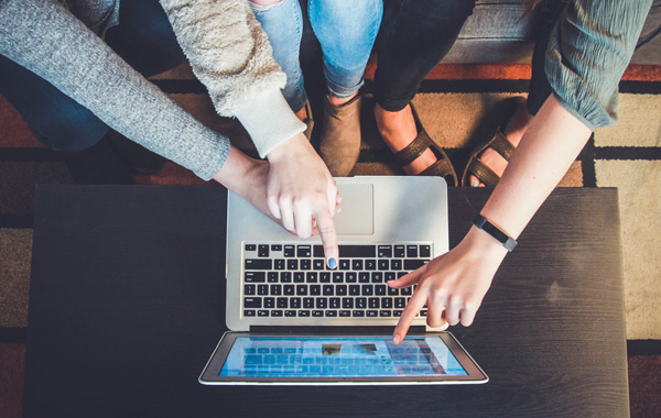 group of people pointing towards the laptop