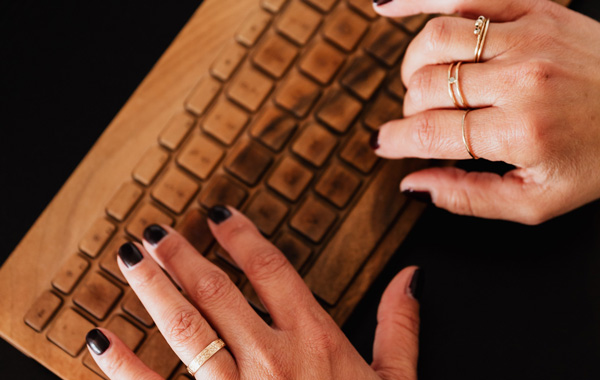 hand of a woman typing using a wooden keyboard