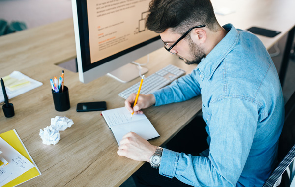 man wearing blue long sleeve writing notes