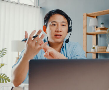 Young asia businessman wear headphones using laptop talk to colleagues