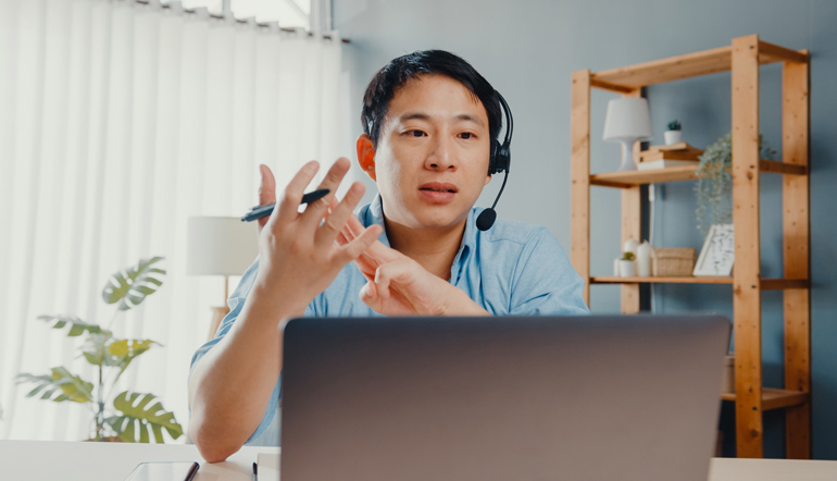 Young asia businessman wear headphones using laptop talk to colleagues