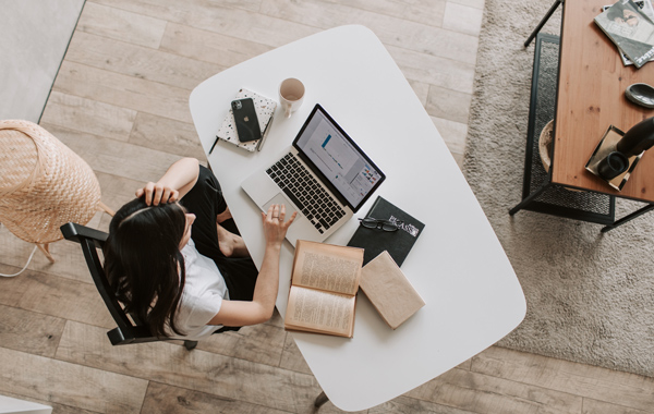 A lady verifying facts from a book while proofreading an academic paper