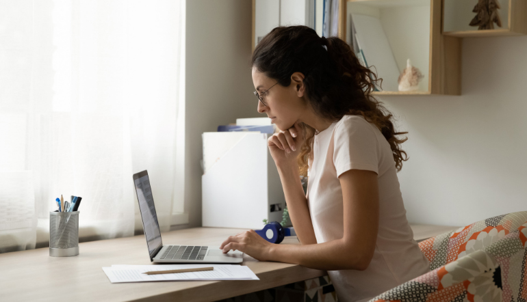 lady working at a desk with a laptop and a paper beside her