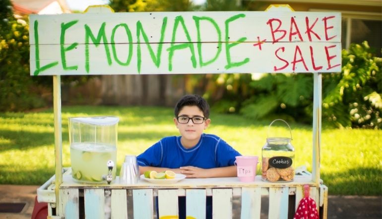 boy wearnig blue shirt selling lemonade