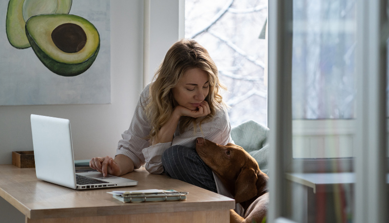 blonde woman brown dog beside her while working