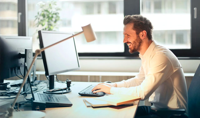 man working on computer while smiling