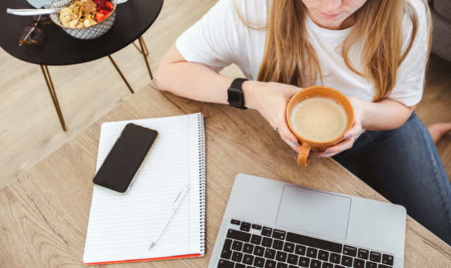 Woman working from home with laptop and large cup of coffee