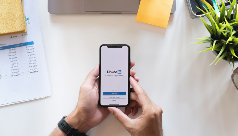 person holding smartphone with LinkedIn on screen