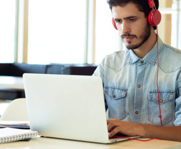 male with red headphone using laptop