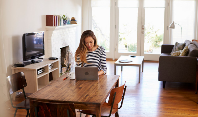 woman working from home using laptop on dining table