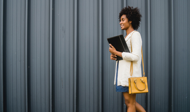 adult woman holding a book while walking