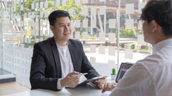 man seated and interviewing a male candidate