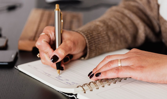 hands of a woman writing on a notebook