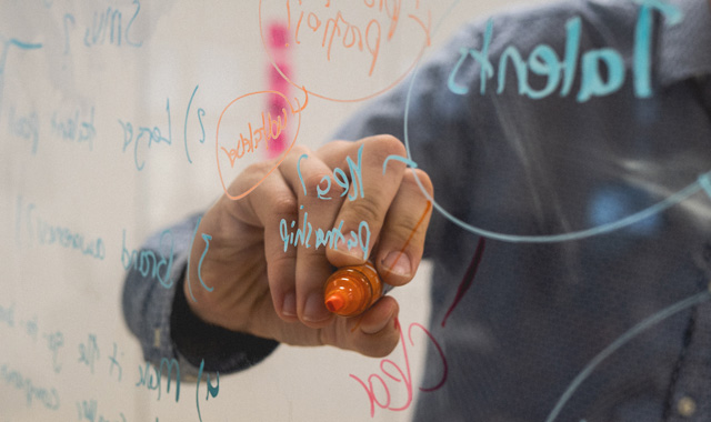 man writing ideas on a glass screen