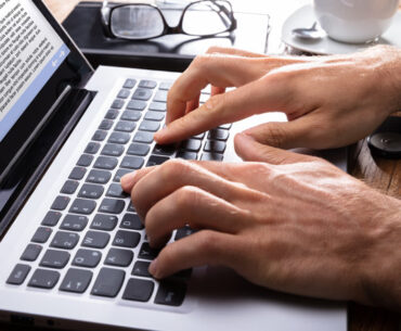 close-up of a person typing on laptop