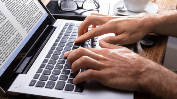 close-up of a person typing on laptop