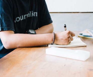 Crop man writing in notebook