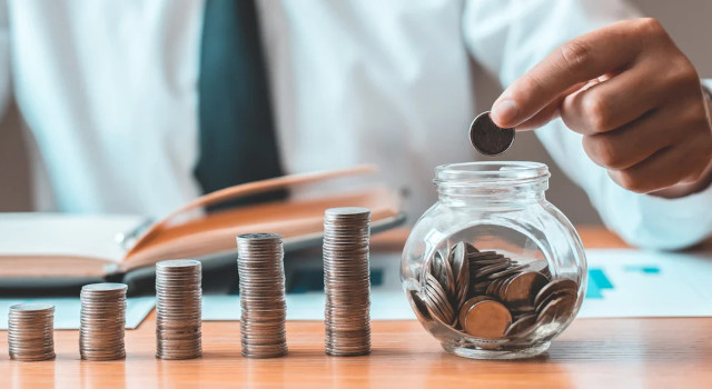 man’s hand putting coins in a jar