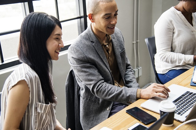 two office workers smiling at a laptop screen