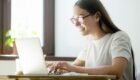 young female smiling in front of her laptop